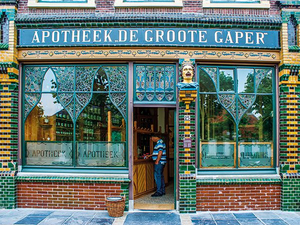 Opieka Farmaceutyczna. Enkhuizen w Holandii. Witryna starej holenderskiej apteki z kultowym symbolem przyjmującego leki gapera.